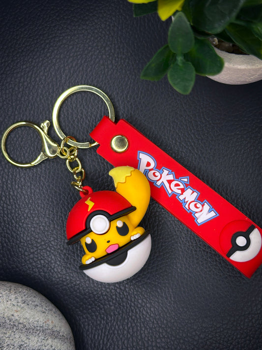 A cute yellow Pikachu peeking out of a red and white Pokéball keychain, attached to a red strap with the Pokémon logo and matching Pokéball icon.