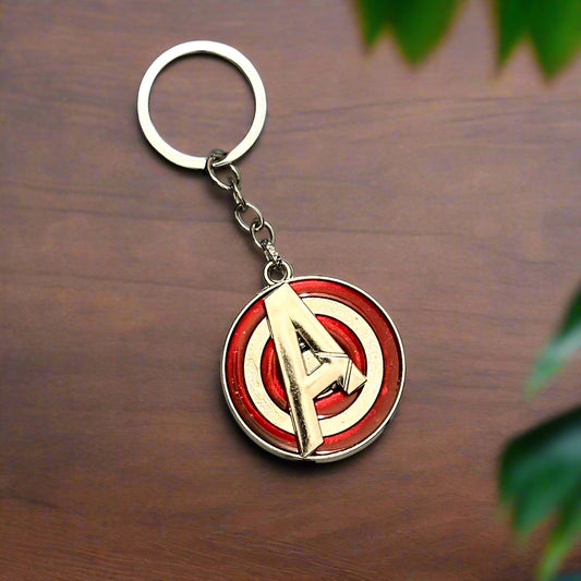 A metallic Avengers "A" logo keychain in red and silver enamel, displayed on a white marble hexagon-tiled background.