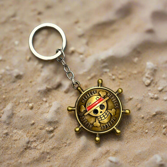 A One Piece-themed bronze keychain shaped like a ship's wheel with Luffy's straw hat pirate logo in the center, placed on a white marble hexagon-tiled background.